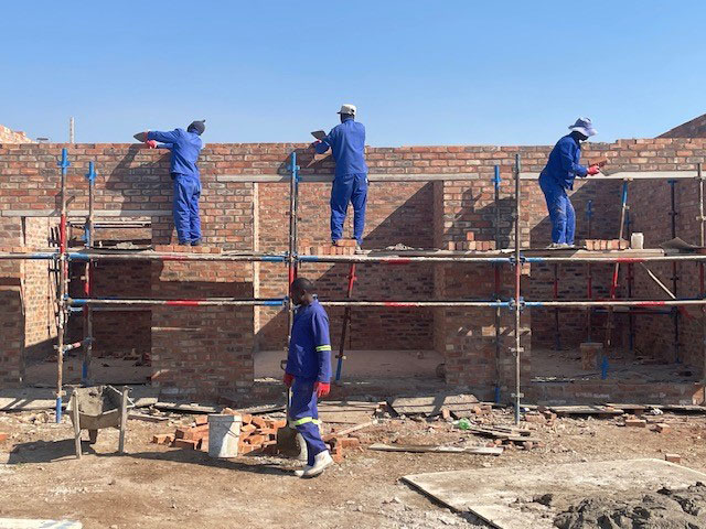 Bricklayers building a wall on scaffolding